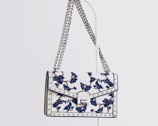 A luxury white and blue floral purse featuring an elegant chain strap