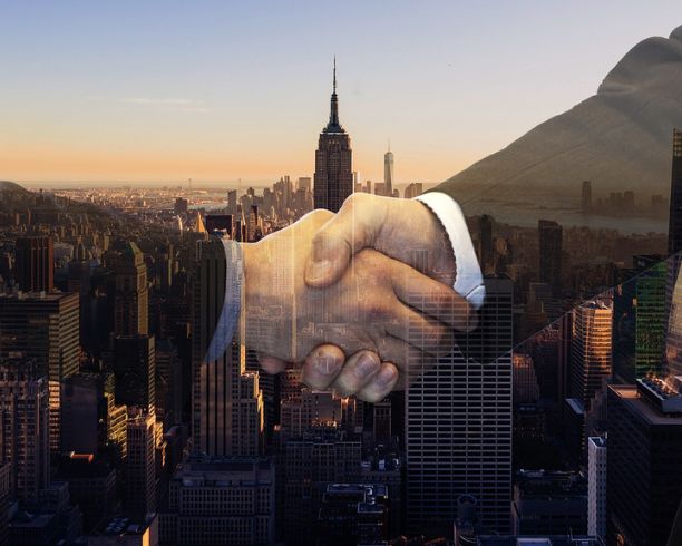 Businessmen shake hands with the Empire State Building visible in the cityscape behind them