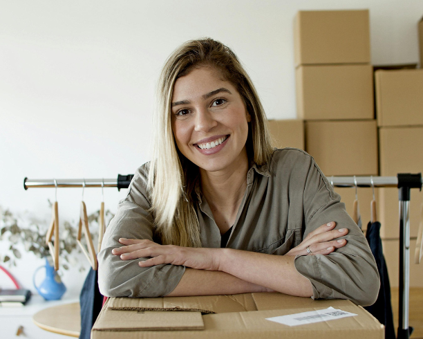 A woman with a bright smile surrounded by boxes